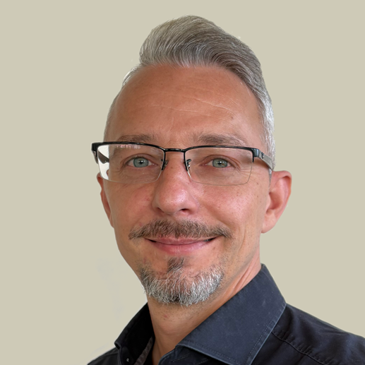 Mann mit gestylten grauen Haaren, Brille und getrimmten Bart